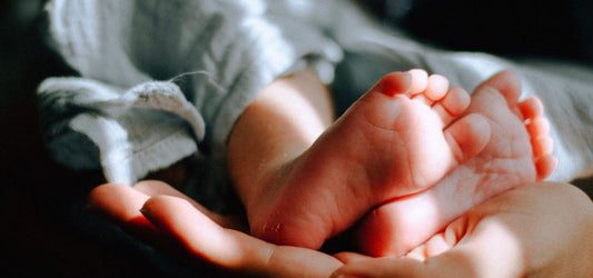 woman's hand holding baby feet
