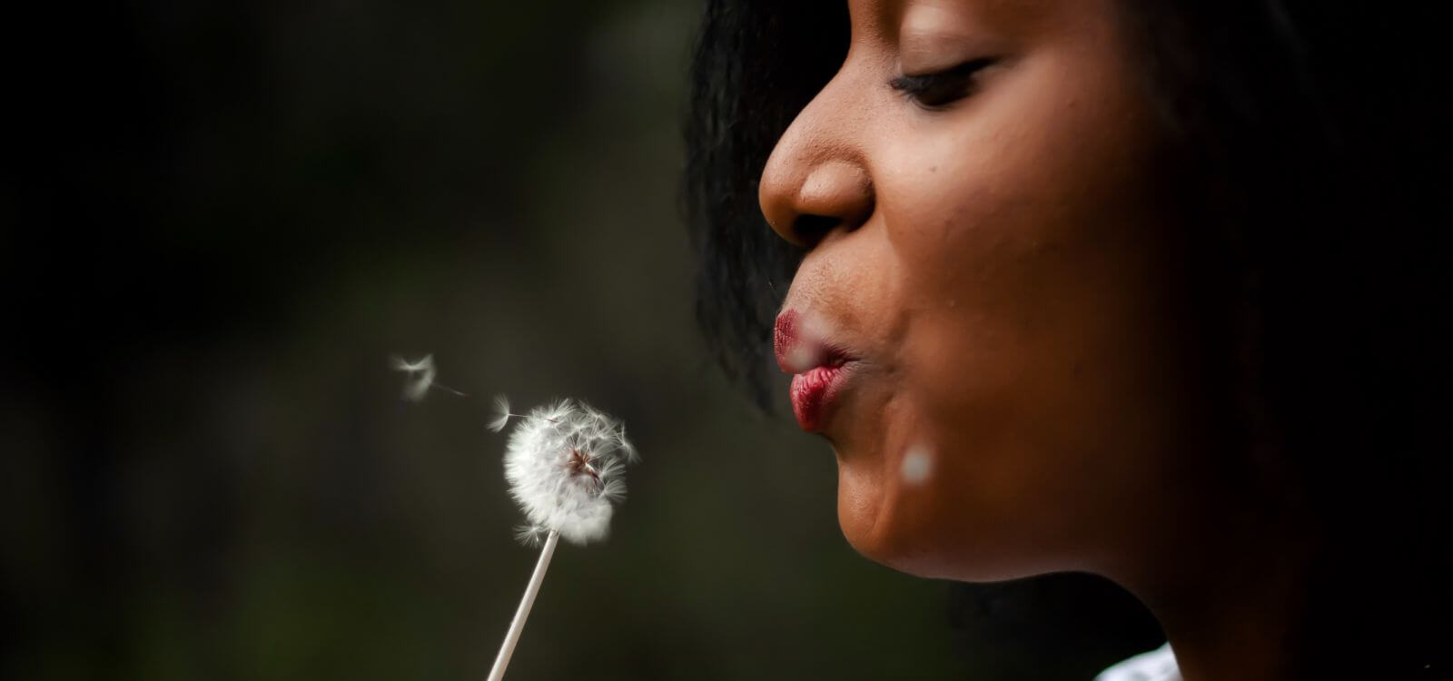 Woman blowing a dandelion