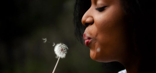 Woman blowing a dandelion