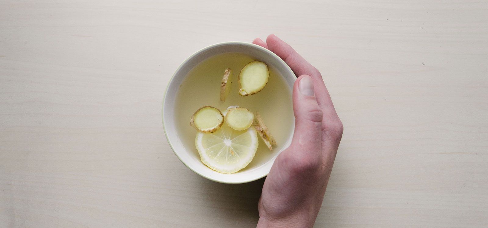 Person holding mug with sliced ginger