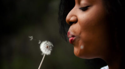 Woman blowing a dandelion