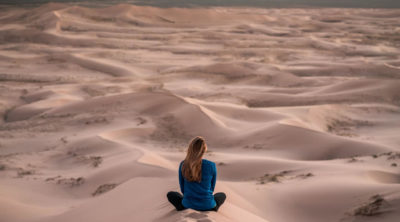 woman meditating in dunes