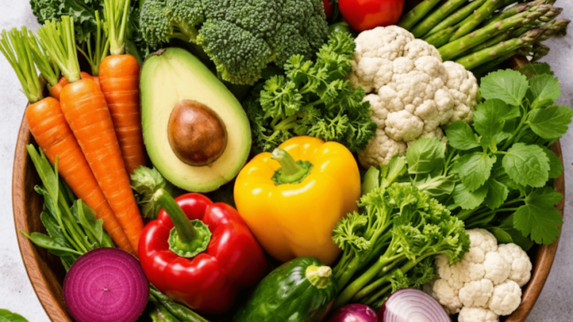 wooden harvest bowl filled with a rainbow of produce, including leafy greens, root vegetables, and cruciferous favorites
