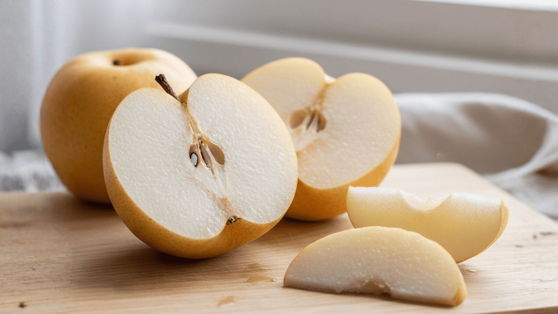 Fresh Asian pear slices placed on a wooden board, showcasing its crisp texture and light yellow color