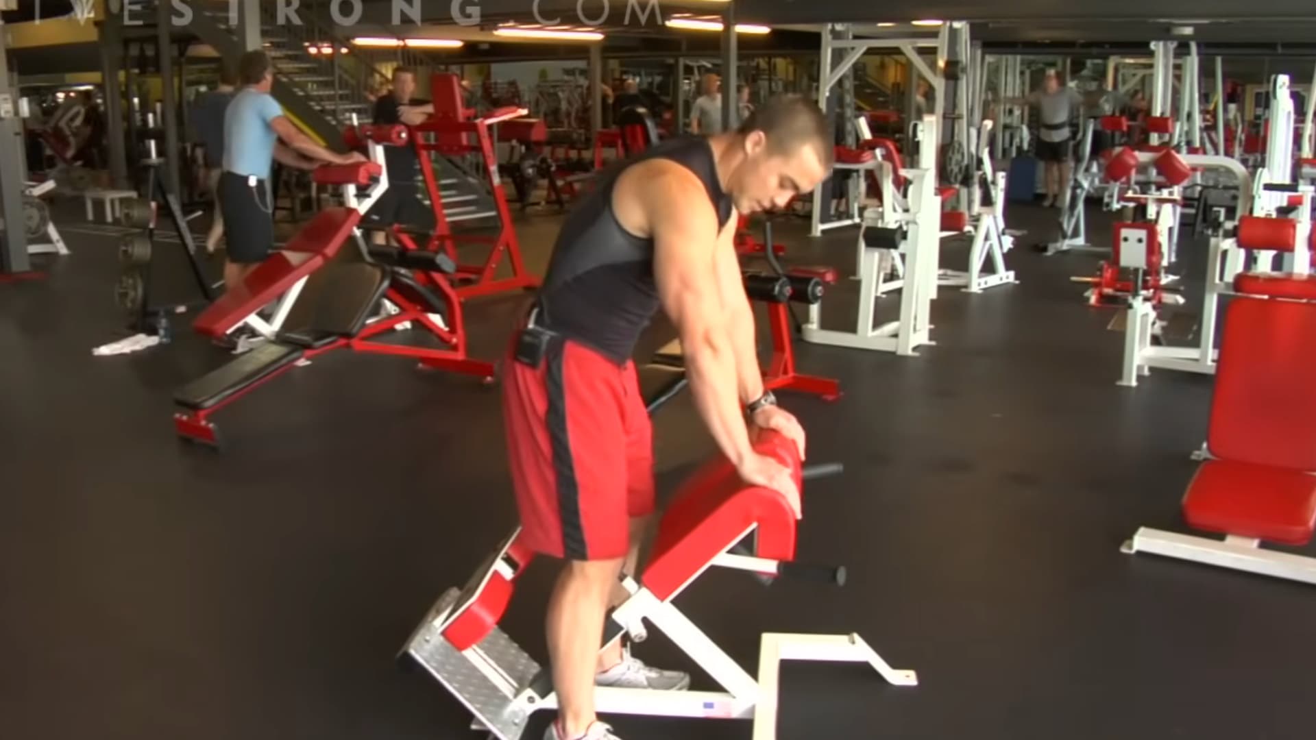 a gym preparing to use a red hyper-extension machine for lower back and posterior chain strengthening