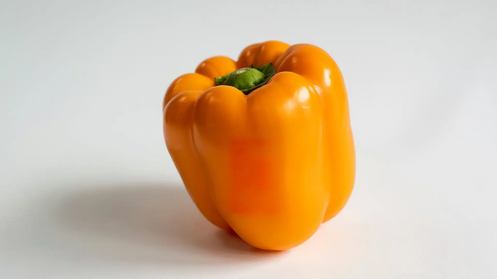 orange bell pepper with smooth skin and a bright green stem, showcasing its natural freshness and color