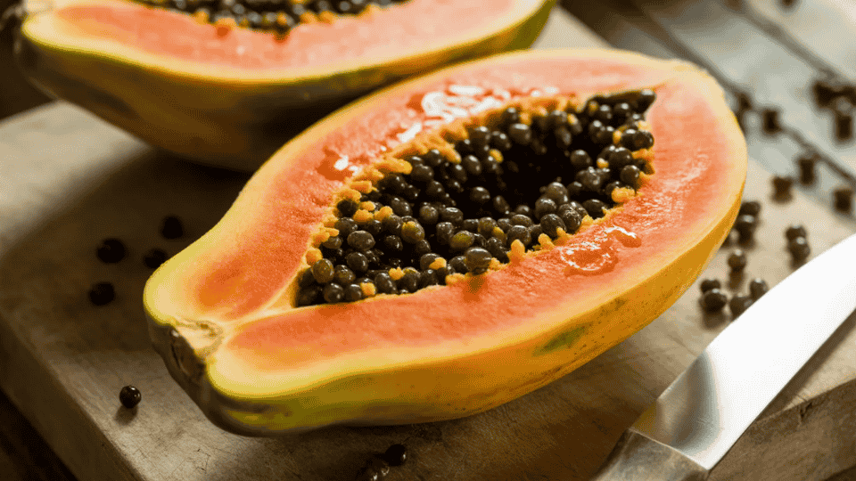 papaya cut in half on wooden board showing orange flesh and black seeds naturally high in potassium for healthy diet