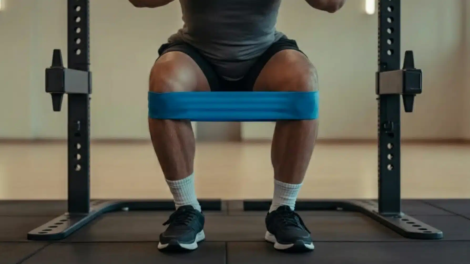 person performing banded squat with resistance band around thighs, focusing on knee alignment and glute activation in gym setting
