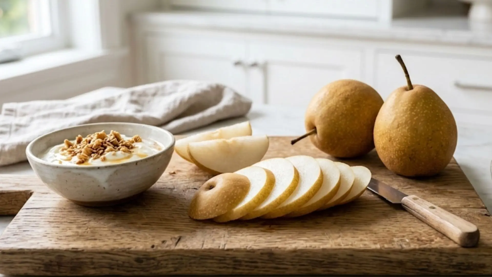 sliced asian pear, greek yogurt, and mixed nuts on a wooden board in a bright, sunlit, clean modern kitchen setting