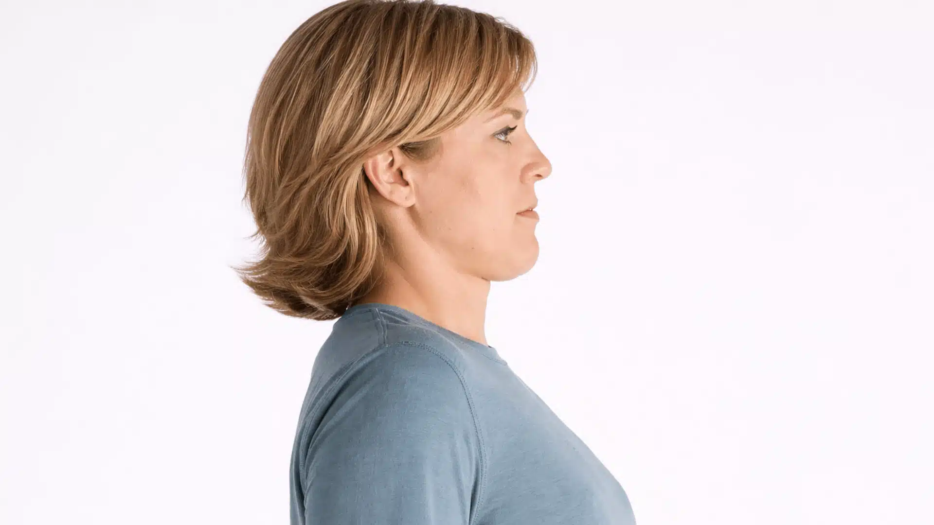 a woman performing a chin tuck exercise, creating a double chin while maintaining proper neck alignment