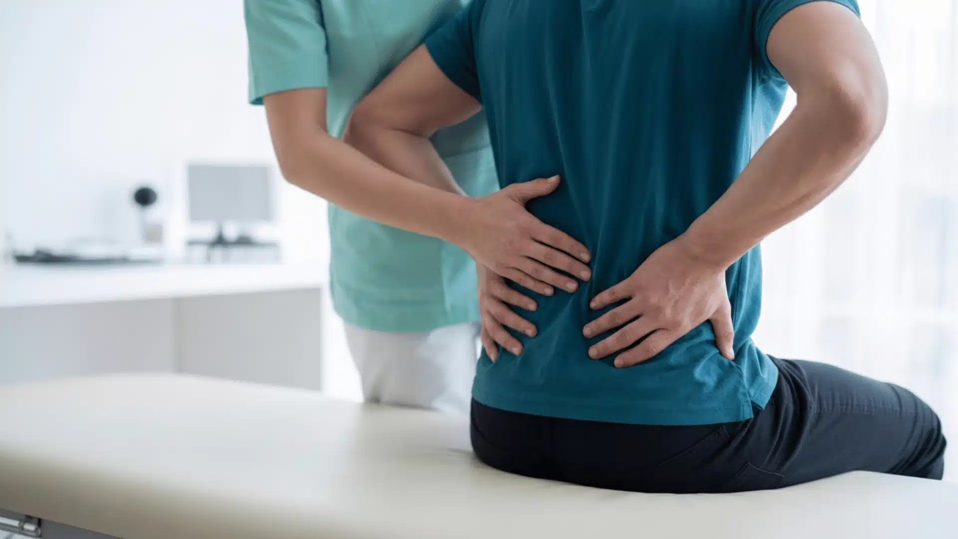 healthcare professional wearing mint green scrubs is examining a patient's lower back