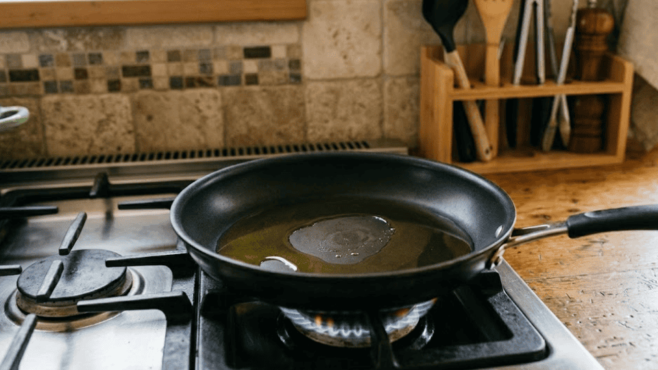 olive oil warms gently in a non-stick pan over a low gas flame