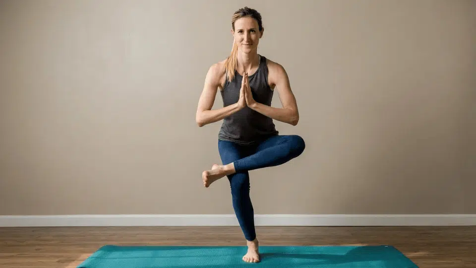 standing figure four balance pose ankle resting over opposite knee while sitting back to stretch hips and build leg stability
