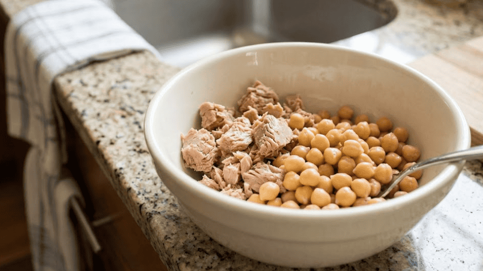 tuna and chickpeas in a white bowl on a granite counter with a fork