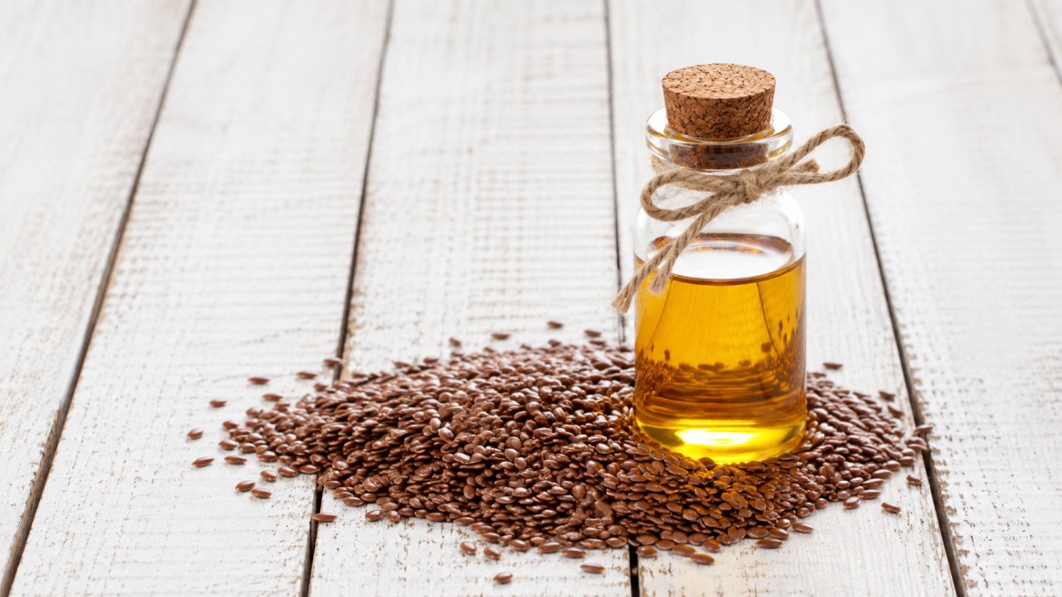 A small glass bottle of golden flaxseed oil, with a cork stopper and twine bow