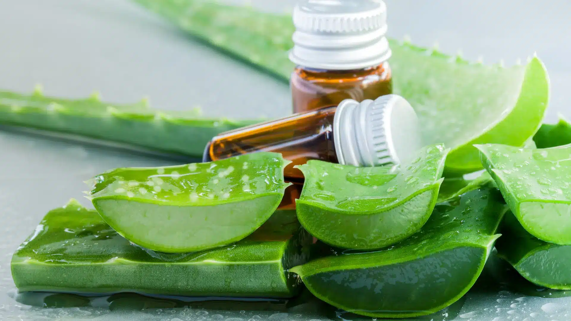 aloe vera leaf slices with gel and small amber bottles, representing aloe vera skincare and natural face care benefits