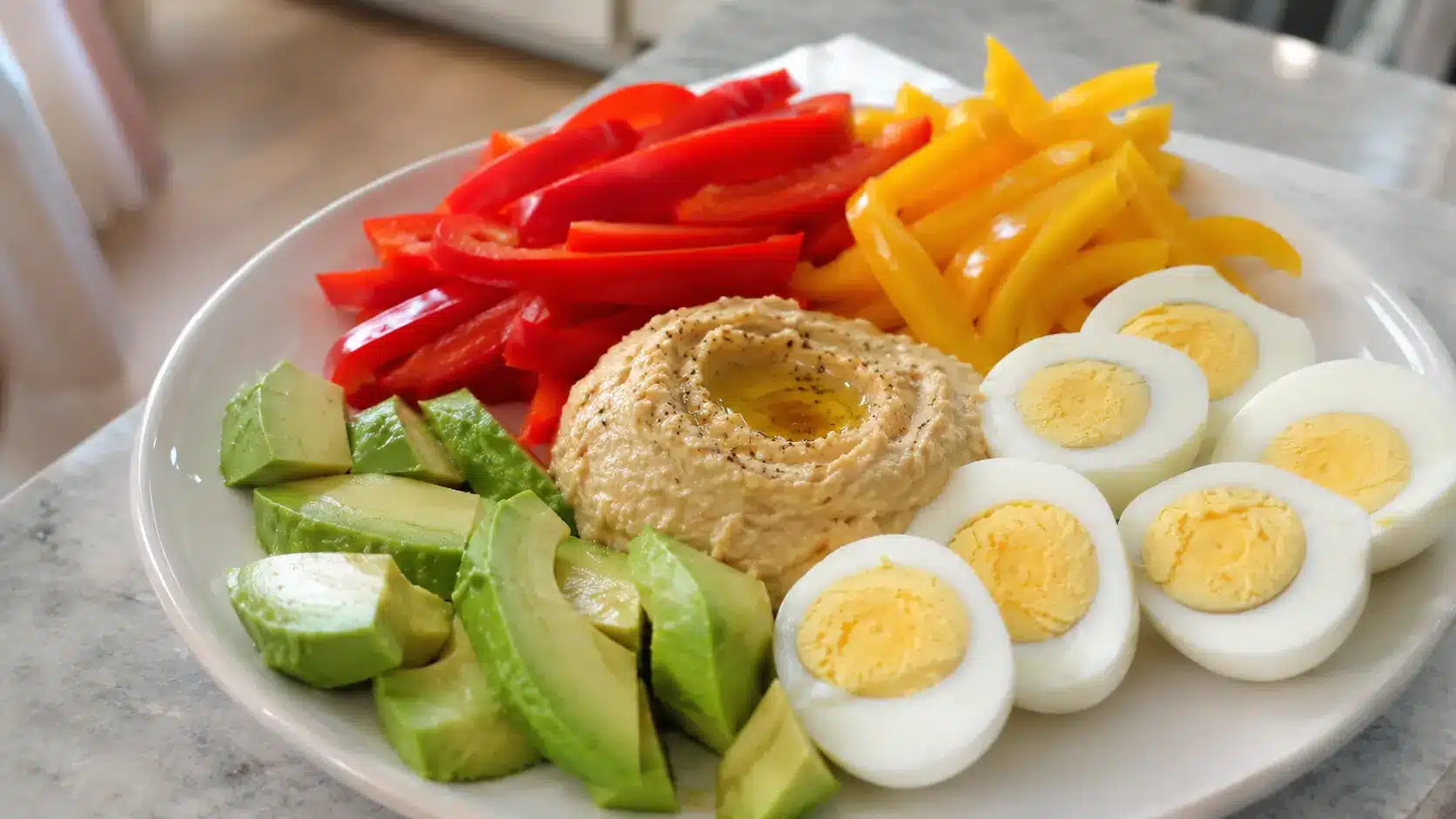bell peppers hummus eggs and avocado on a snack plate