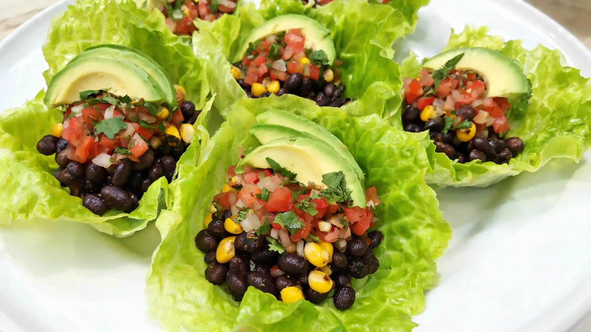black bean and corn mixture wrapped in crisp lettuce leaves with fresh pico and avocado