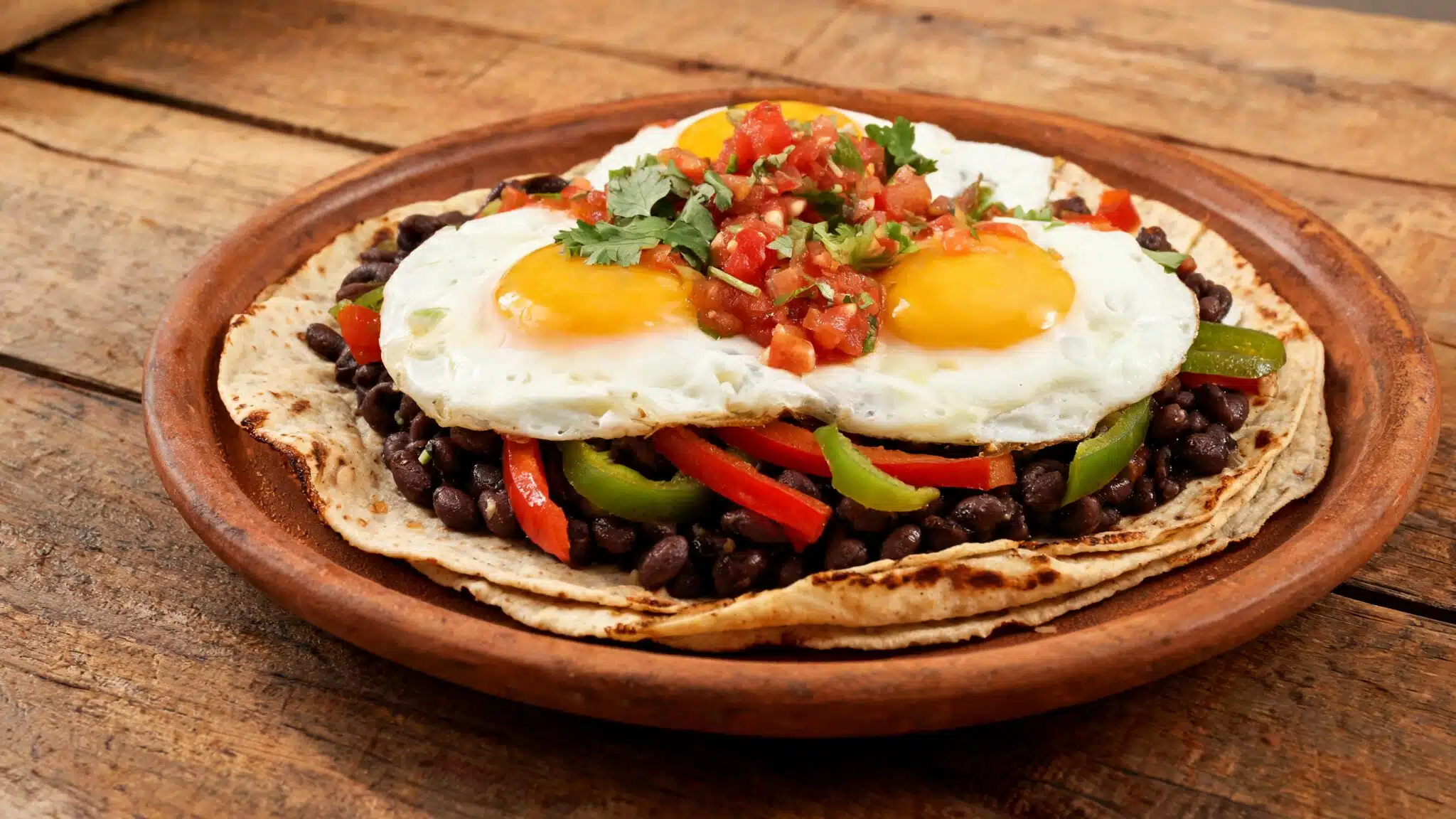 eggs served over corn tortillas with black beans, bell peppers, and fresh salsa for a hearty meal
