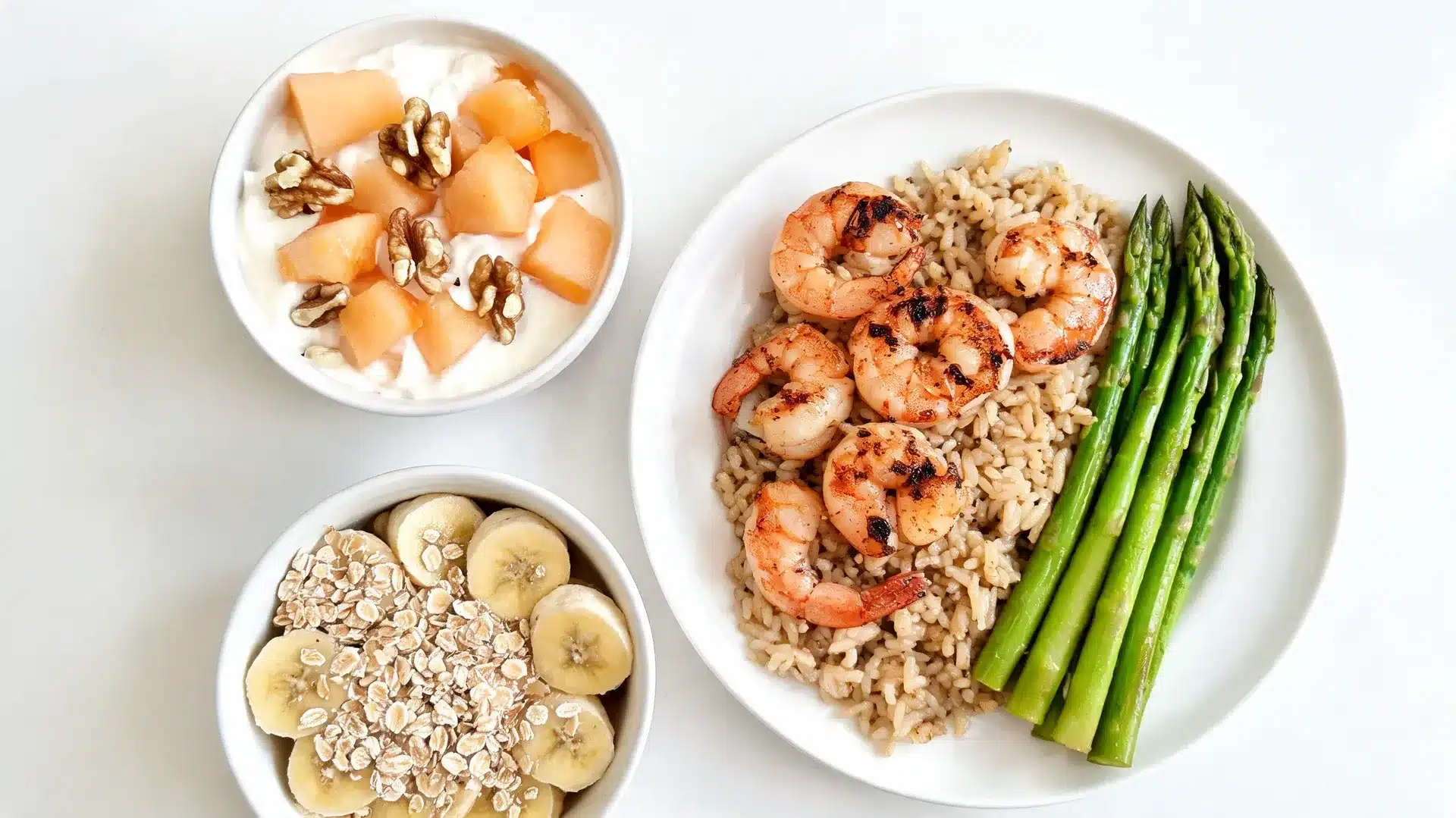 plate with grilled shrimp, brown rice, asparagus, yogurt with melon and walnuts, plus banana slices topped with oats