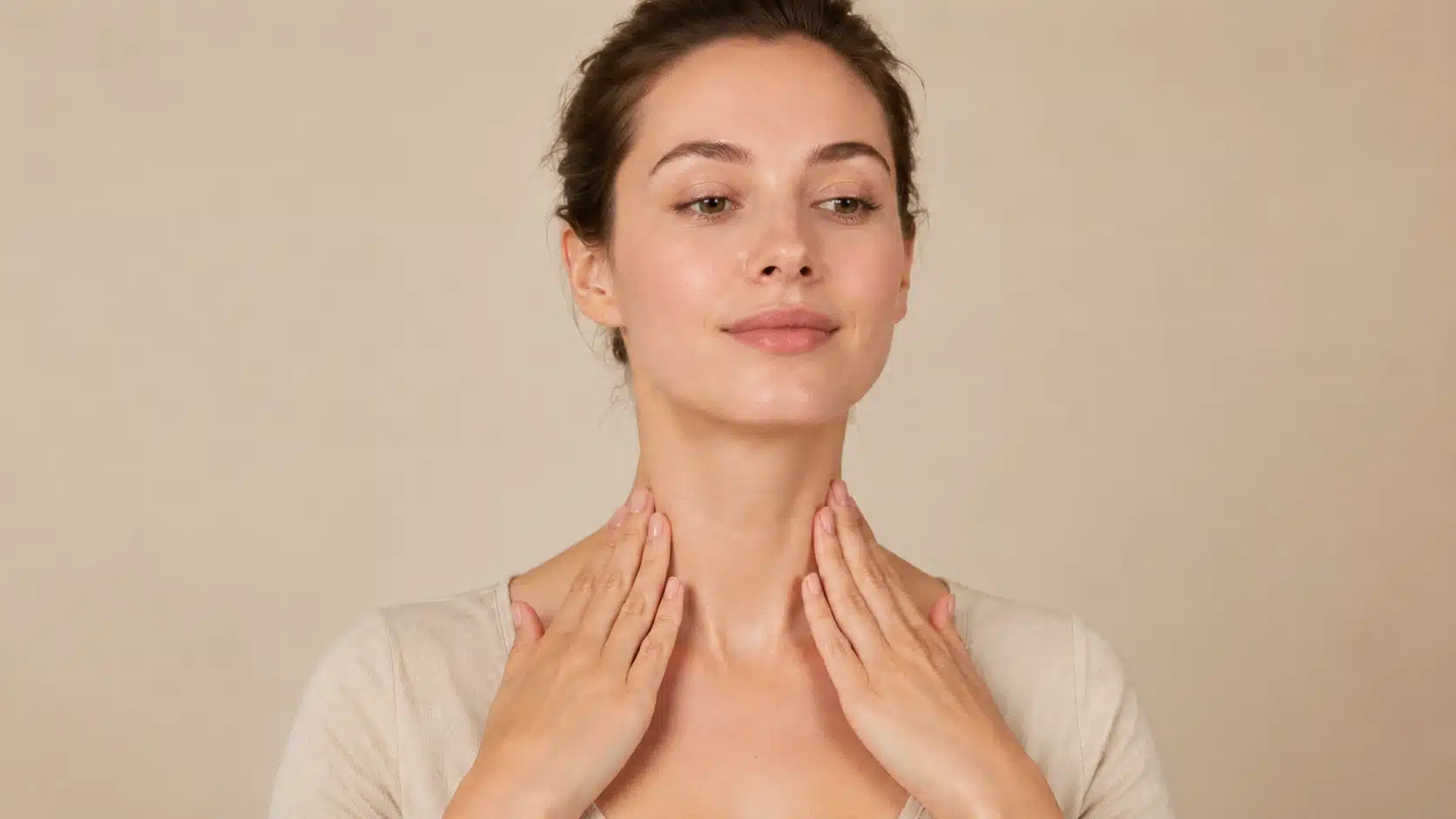 woman finishing facial massage with light downward neck strokes toward collarbone in neutral setting calmly