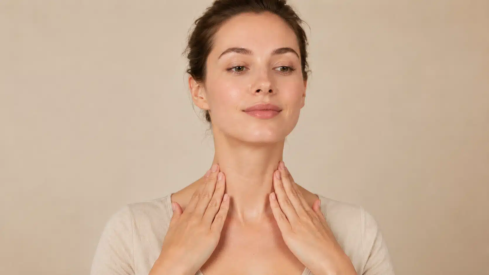 woman using gentle downward strokes on neck and collarbone during facial massage routine at hom
