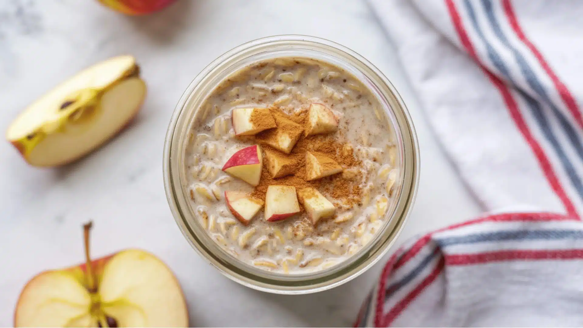oats in a clear glass mason jar the oats have a creamy beige color and are topped with diced red apples