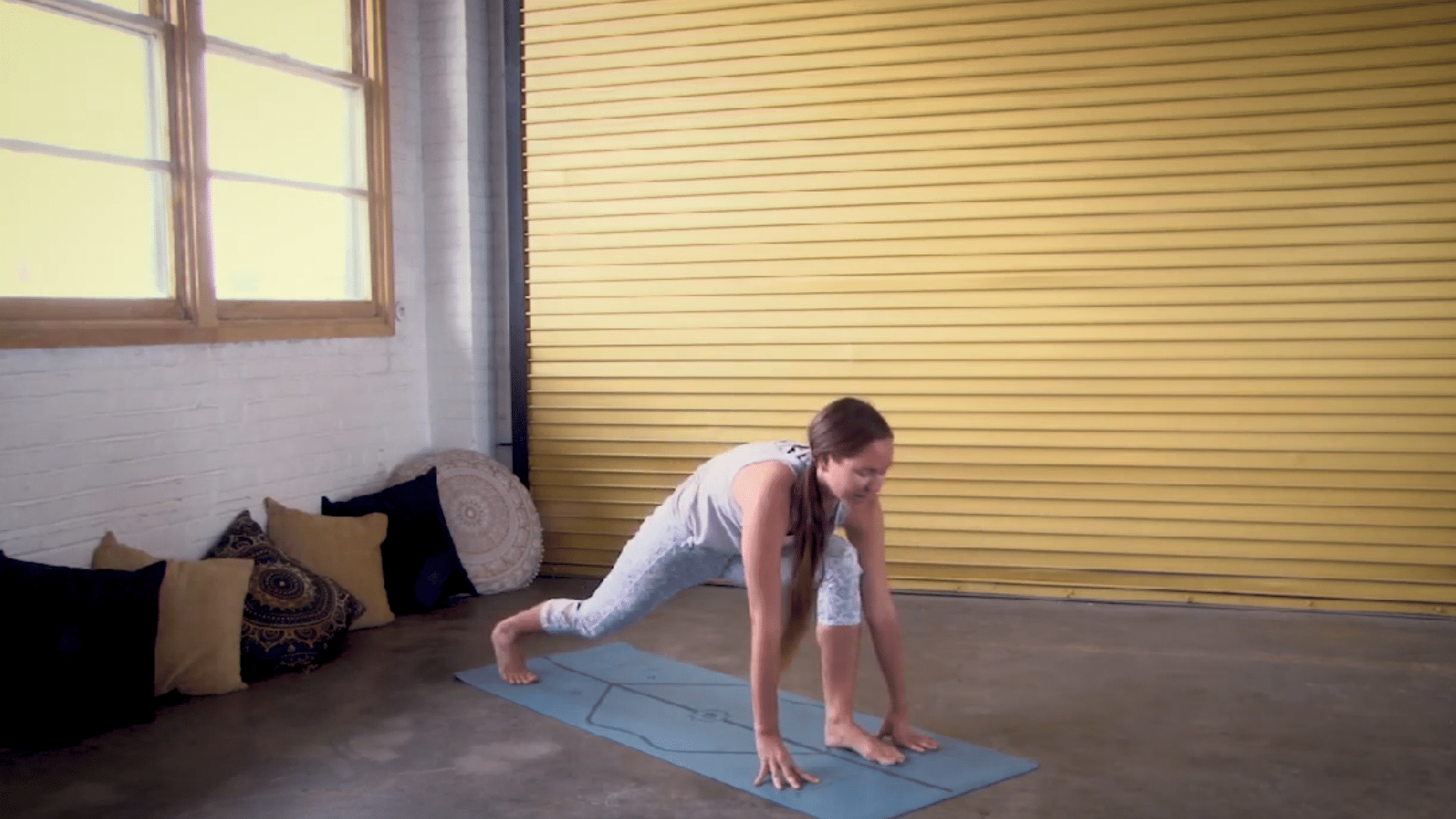 person using hands for support while stepping out of a low lunge before switching sides