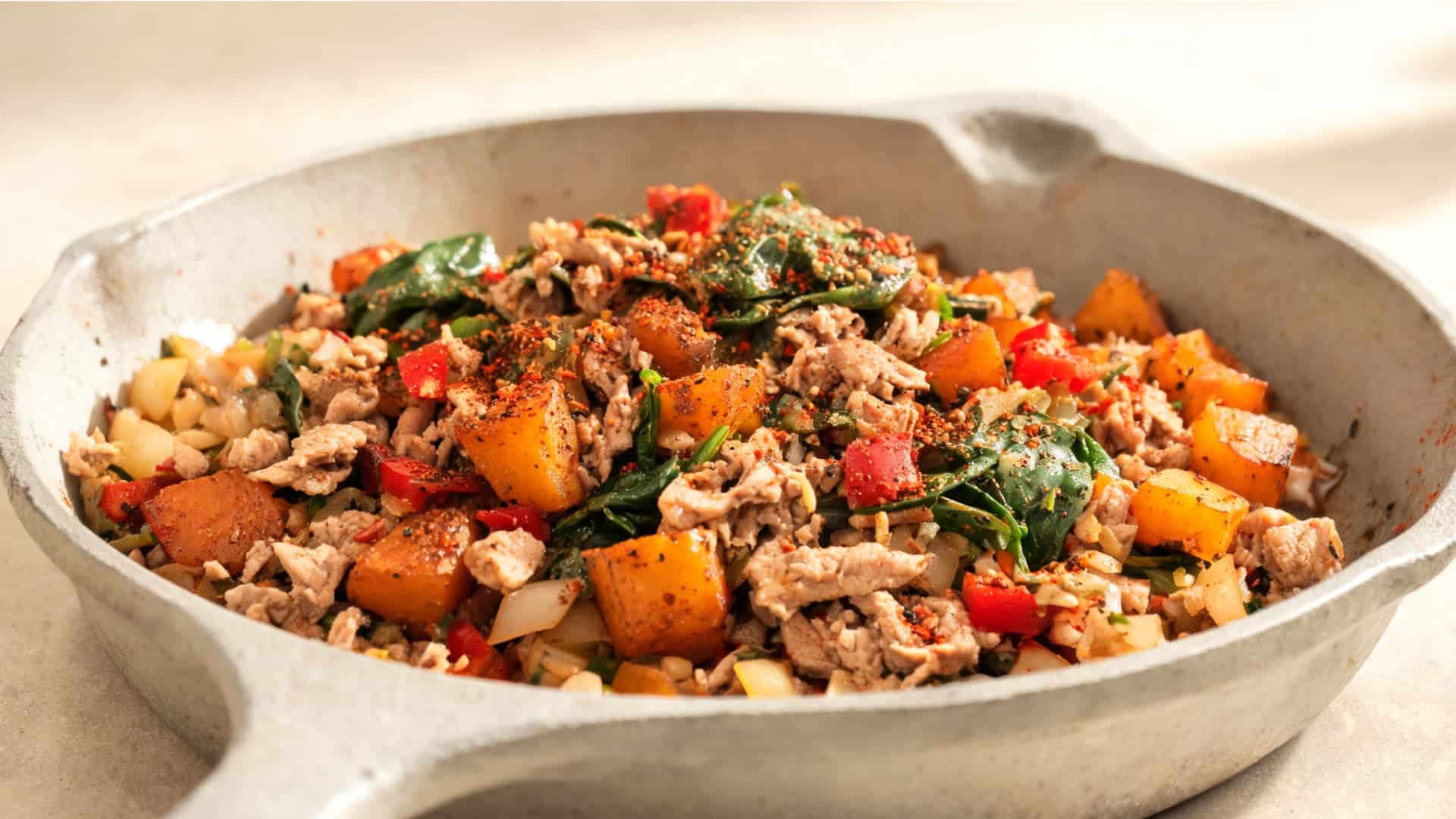 savory breakfast skillet with ground turkey, sweet potatoes, spinach, peppers and spices in a rustic pan