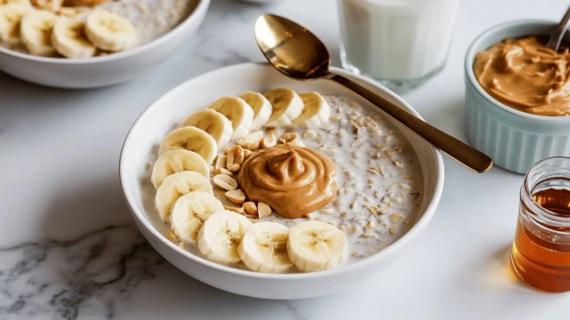 white ceramic bowl on a white marble surface the oats are topped with fresh, thinly-sliced bananas arranged