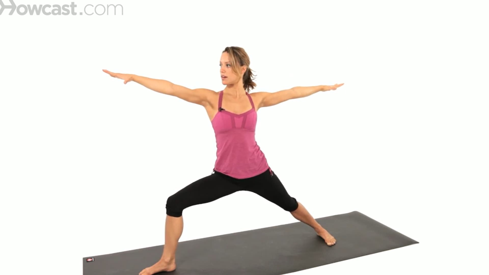 woman holds warrior ii on a mat with arms extended, front knee bent, and steady focused posture