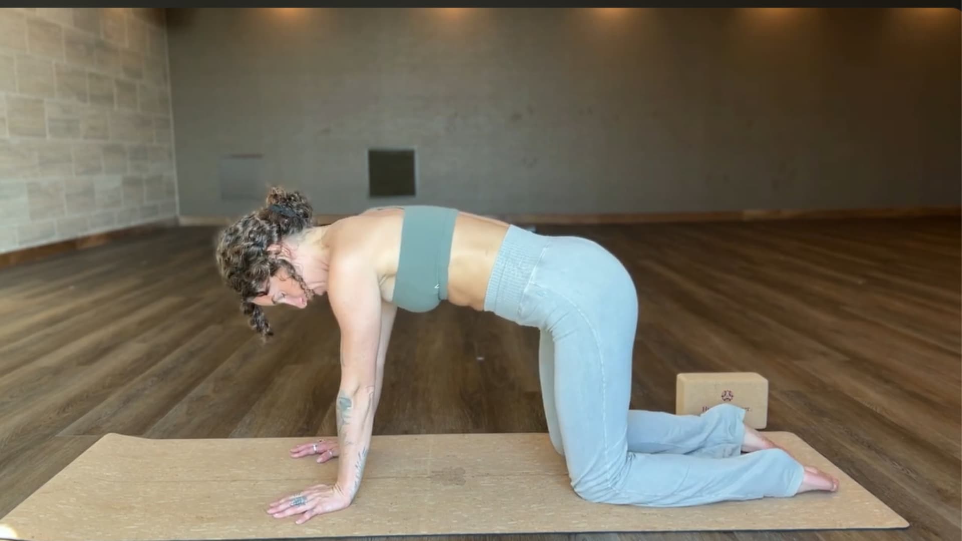 woman in tabletop position on a yoga mat setting up for puppy pose practice
