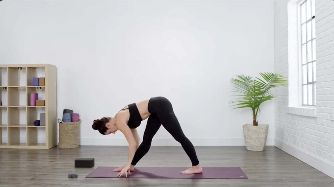 woman placing her hands near the front foot while folding into pyramid pose