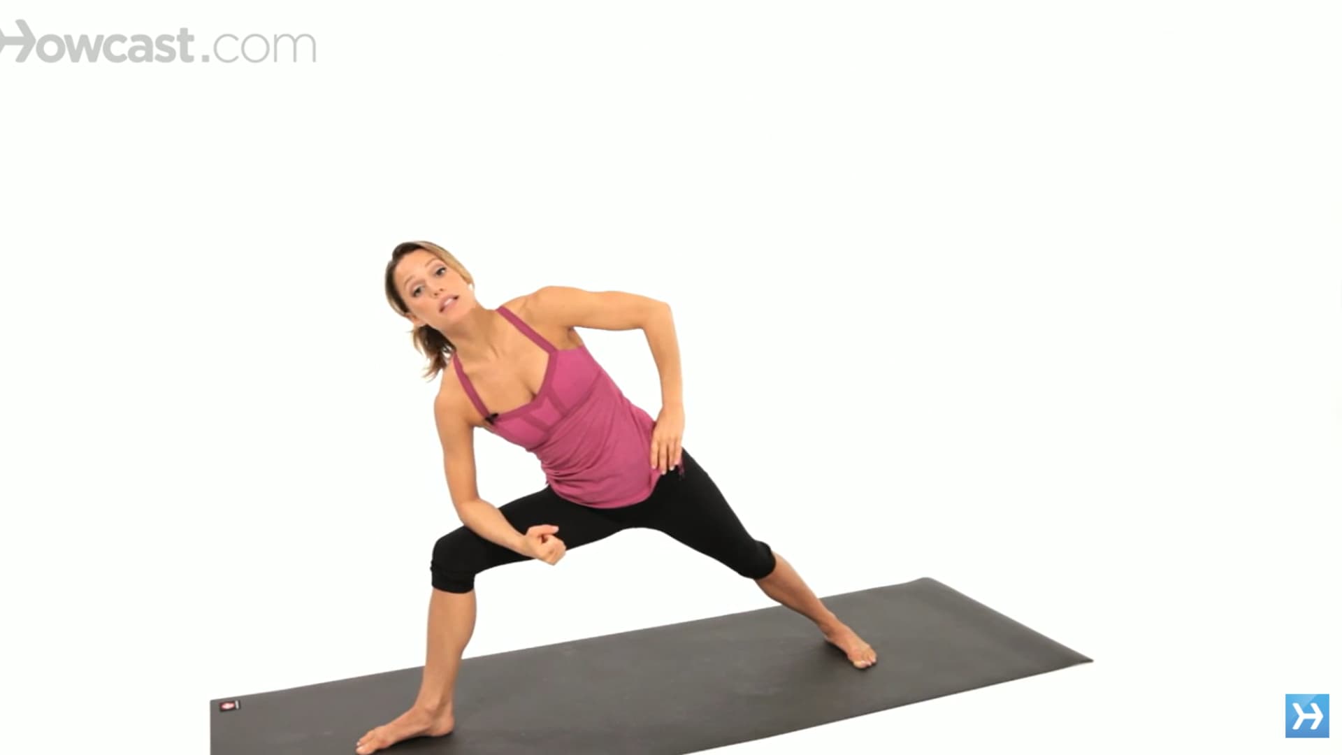 woman practices side angle pose with forearm on thigh and top hand on hip in a wide stance mat pose