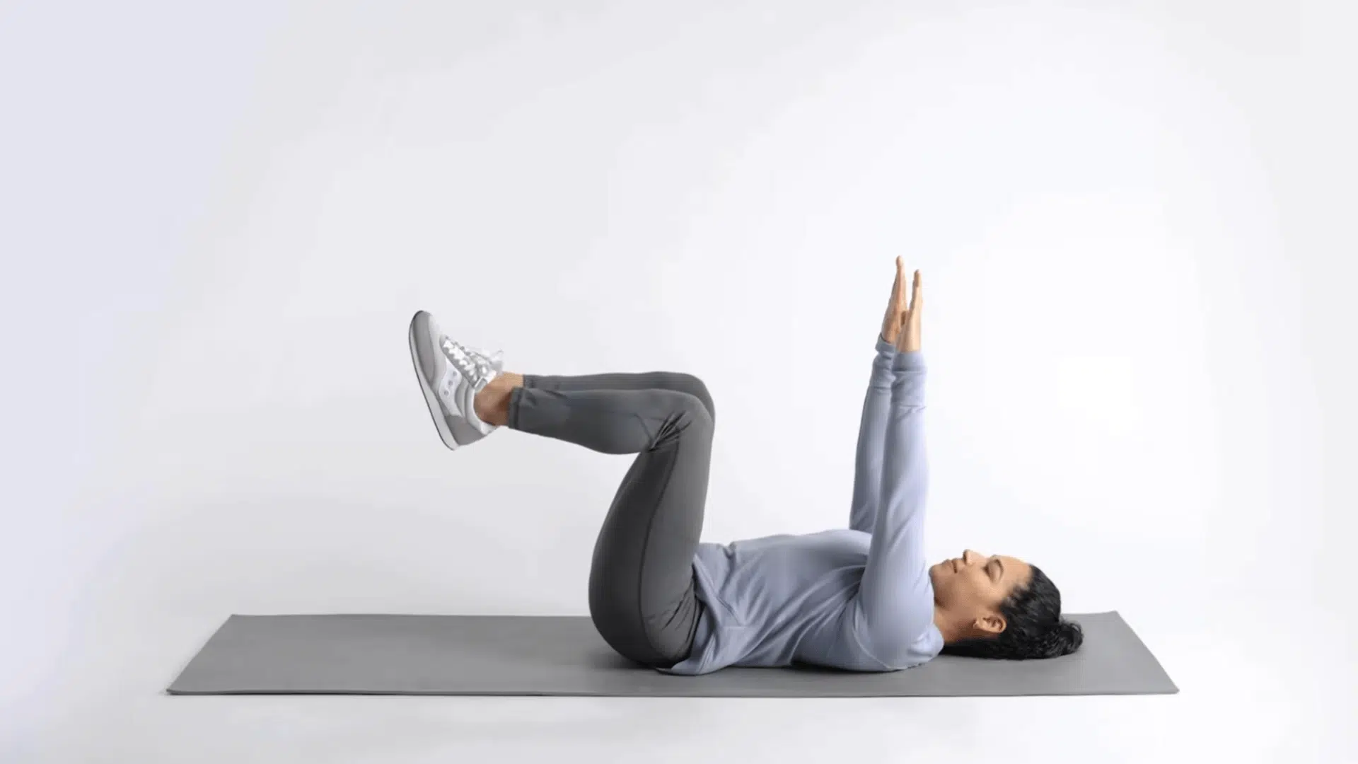 woman lying on mat in tabletop starting position with arms up and knees bent