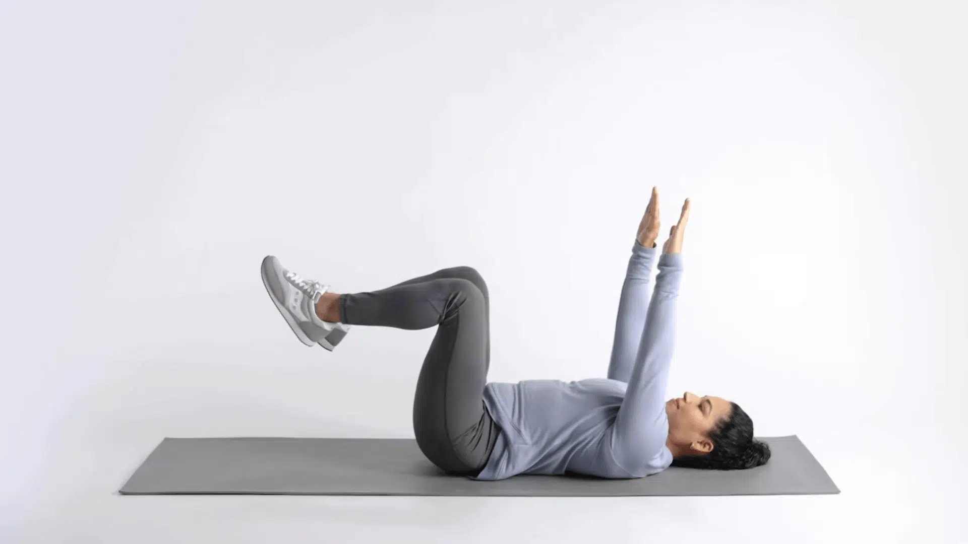 woman on mat extending one arm and opposite leg during dead bug exercise repetition