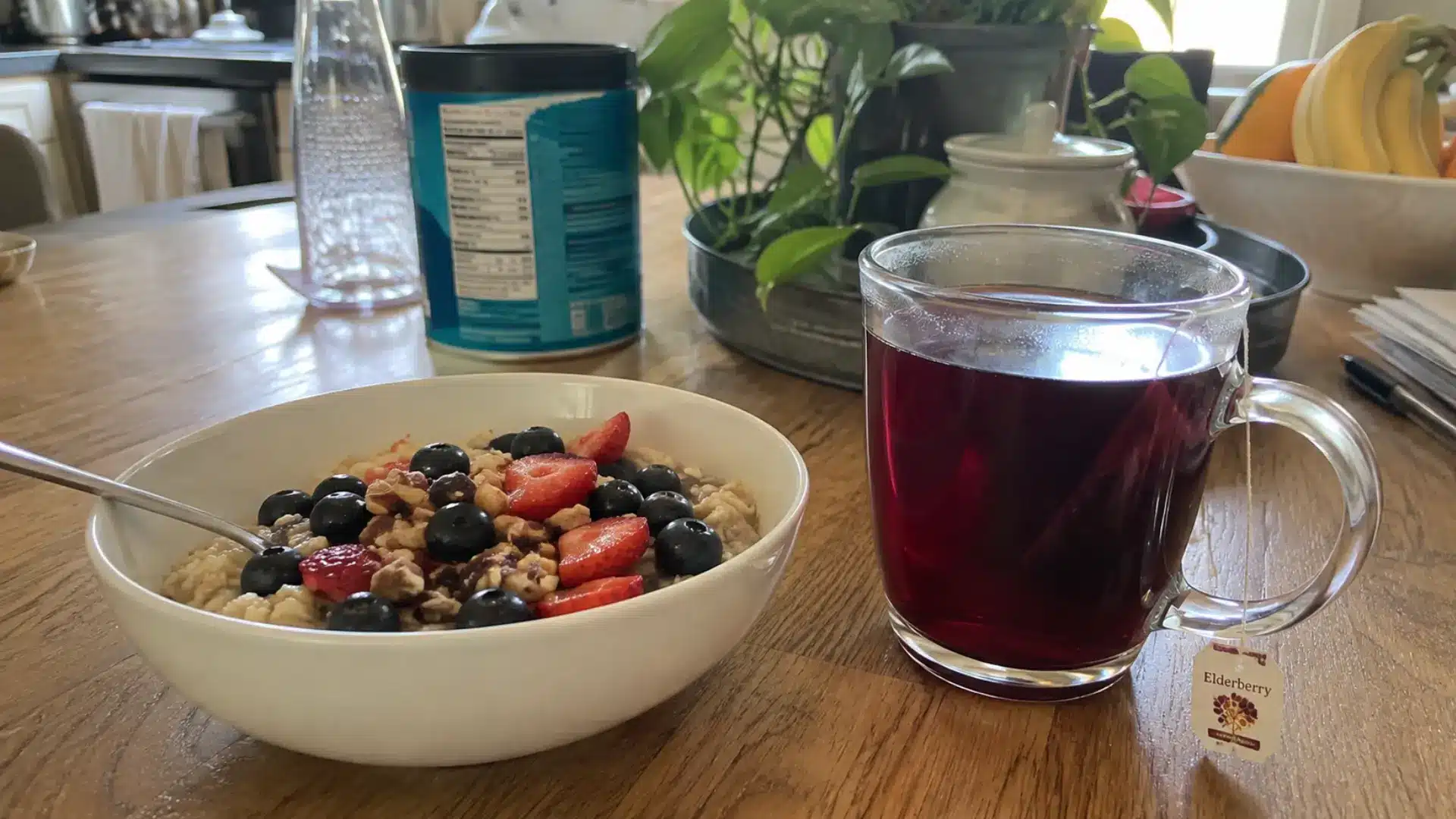 mug of elderberry tea beside a bowl of oatmeal with fresh berries